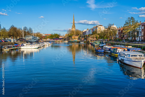 Bristol, England, UK - April 2023: The gothic church of Saint Mary Redcliffe on the shores of river Avon with boats docked in the harbor photo