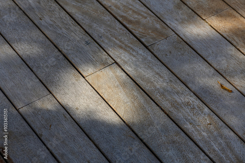 Sunlight dances on weathered wooden planks, revealing intricate textures and natural hues in a serene outdoor setting