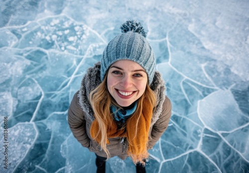 Top view of attractive woman smiling and standing on ice covered lake surface dressed in winter clothes with her hair down, shot from straight above. photo