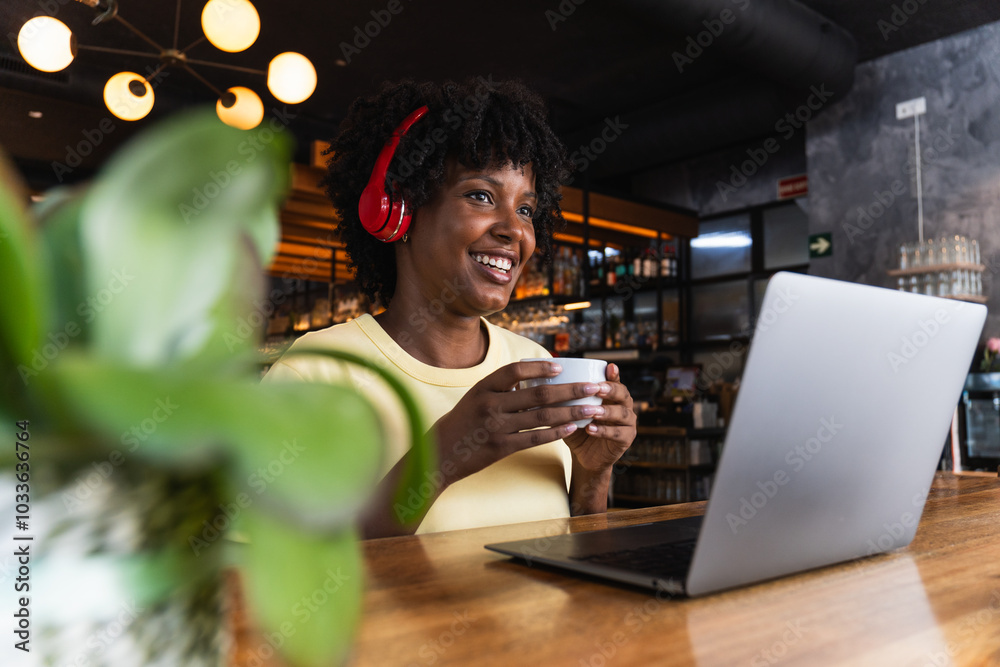 Cheerful woman in headphones using laptop in cafe Cheerful woman in headphones using laptop in cafe