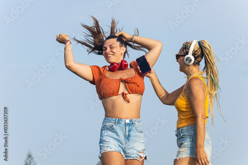 Joyful mother and transgender daughter dancing outdoors photo