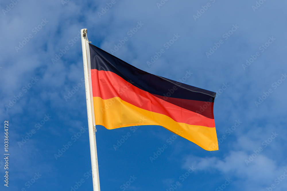 Waving German flag against a clear blue sky in a well-lit outdoor setting during the day Waving German flag against a clear blue sky in a well-lit outdoor setting during the day