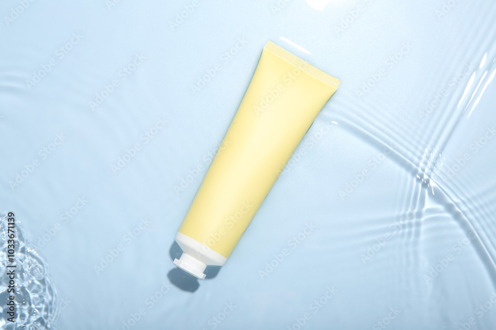 Cosmetic product. Tube with cream in water on light blue background, top view Cosmetic product. Tube with cream in water on light blue background, top view