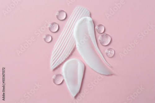 Smears of different cosmetic products on pink background, top view