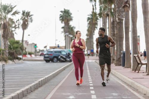 Wallpaper Mural A couple jogging together on a coastal pathway lined with palm trees during a sunny day in a vibrant beach community Torontodigital.ca