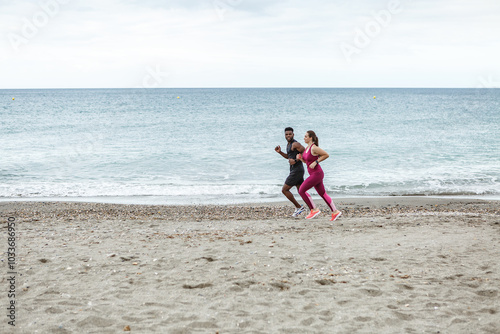 Couple jogging on the sandy beach at Playa del Zapillo in Almeria, Spain, enjoying a refreshing morning workout by the sea photo