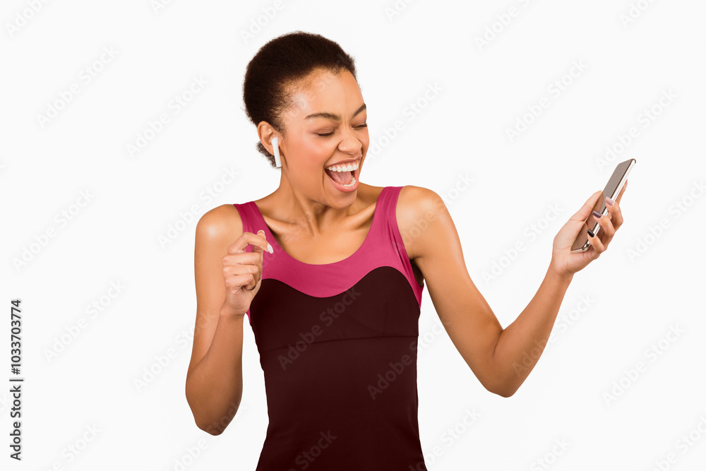 Fitness Workout Music. African American Girl In Wireless Earphones Listening To Song On Smartphone And Singing In Studio, White Background. Fitness Workout Music. African American Girl In Wireless Earphones Listening To Song On Smartphone And Singing In Studio, White Background.