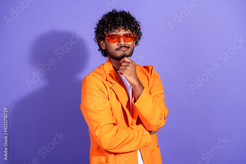 Photo of handsome doubtful guy wear orange suit thinking arm hand chin emtpy space isolated violet color background photo