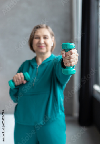 Happy active mature woman with dumbbells in a gym. Sport lifestyle