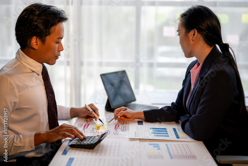 Two people are sitting at a table with papers and a calculator