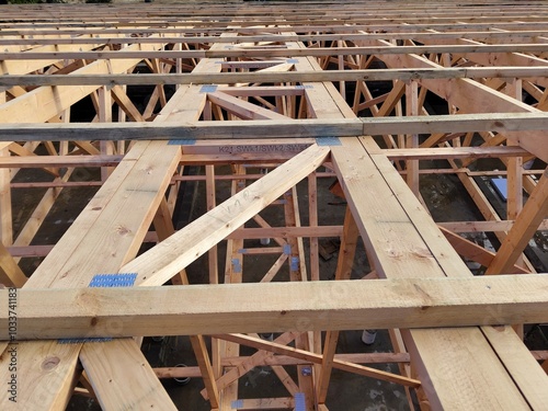 Aerial view of interconnected wooden beams and trusses forming the framework of a large building under construction