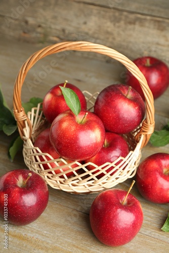 Fresh ripe red apples in wicker basket on wooden table