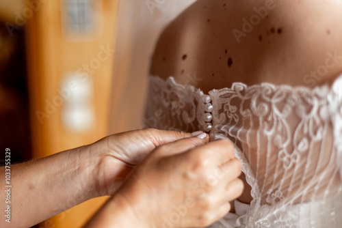 the wedding dress is fastened on the bride's back