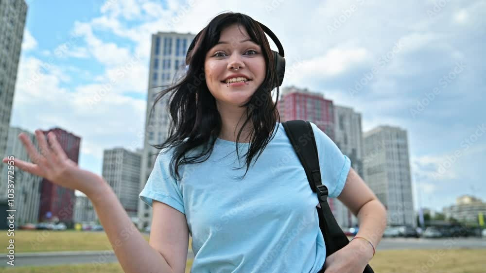 Young confident woman in headphones talking on webcam, outdoor street city Young confident woman in headphones talking on webcam, outdoor street city
