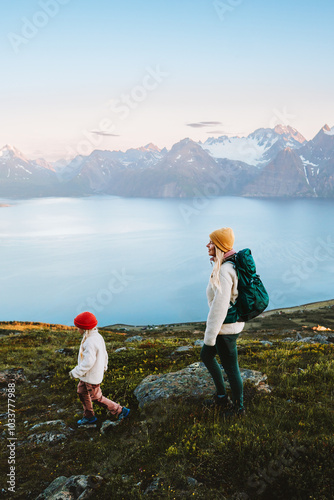 Family traveling mother and child hiking in mountains of Norway backpacking trip in the wild nature, healthy lifestyle vacations outdoor, mom with backpack and kid enjoying Lyngen Alps and fjord view photo