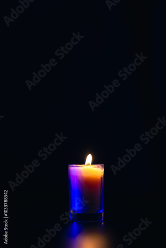 Burning candle on black background with backlight. Memorial Day.