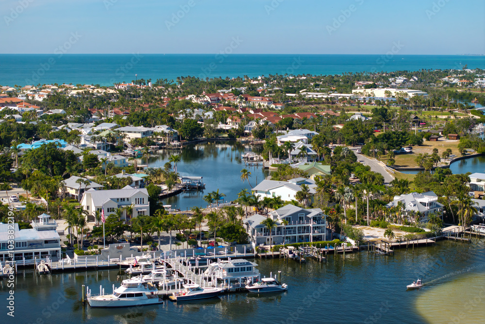 Wealthy neighborhood in small town Boca Grande, Florida with expensive waterfront houses between green palm trees. Development of US premium housing Wealthy neighborhood in small town Boca Grande, Florida with expensive waterfront houses between green palm trees. Development of US premium housing