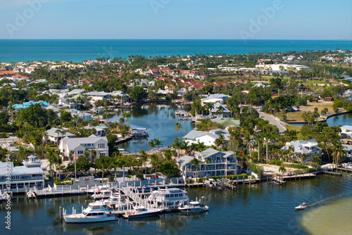 Wealthy neighborhood in small town Boca Grande, Florida with expensive waterfront houses between green palm trees. Development of US premium housing