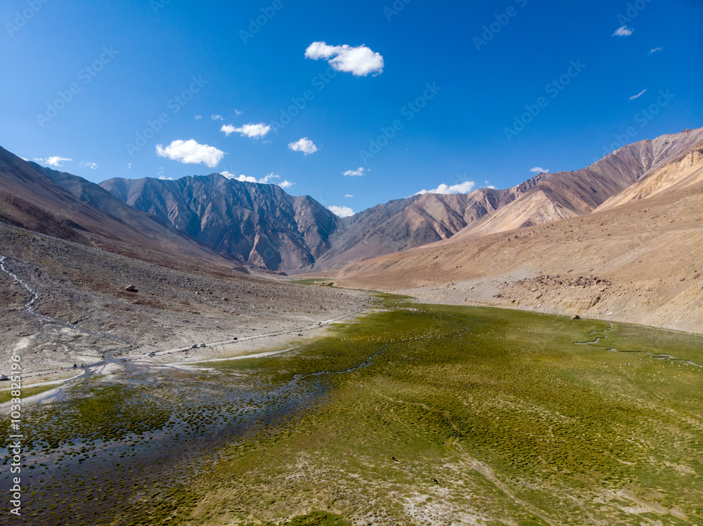 A sweeping view of a serene valley with lush greenery surrounded by majestic mountains under a clear blue sky. A sweeping view of a serene valley with lush greenery surrounded by majestic mountains under a clear blue sky.