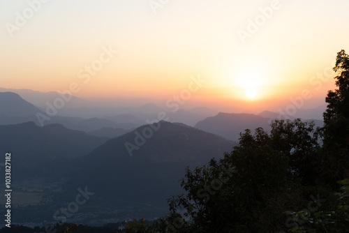 A peaceful sunrise over misty mountains and lush greenery.