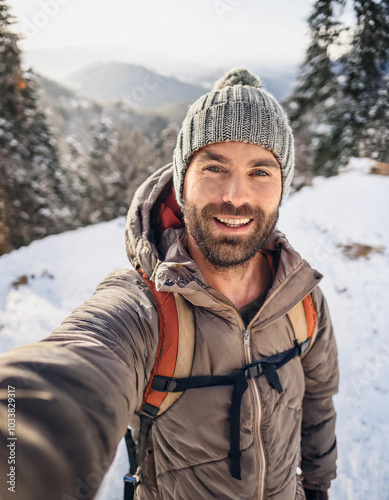 male traveler with backpack taking a selfie portrait walking in the mountains, happy guy having fun outdoors