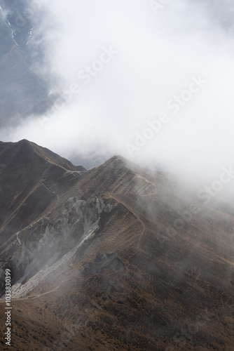 Wallpaper Mural Misty mountain peaks rising through the clouds in a serene landscape. Torontodigital.ca