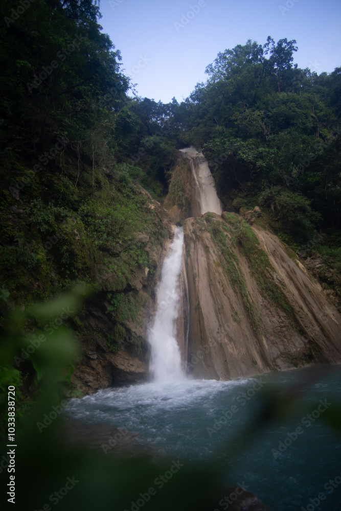 Fototapeta premium A serene waterfall cascading through a lush green forest