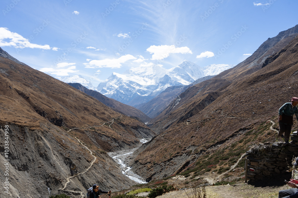 A breathtaking view of a winding mountain valley with distant snow-capped peaks under a clear blue sky. A breathtaking view of a winding mountain valley with distant snow-capped peaks under a clear blue sky.
