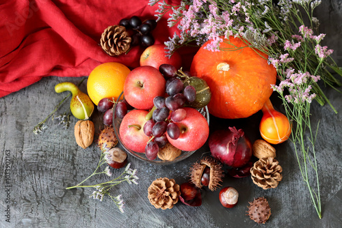 Comfort food ingredients on a table. Colorful still life with pumpkin, apples, nuts and flowers. Autumn harvest concept. 