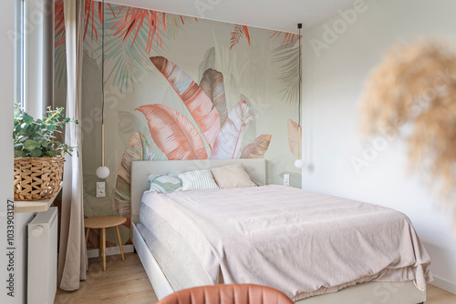 Modern bedroom with textured wallpaper with pattern of leaves. Design interior of room with pillow and comfortable bed. New apartment. Stylish house.	