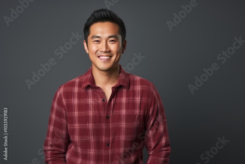 Portrait of a content asian man in his 30s wearing a comfy flannel shirt isolated in soft gray background