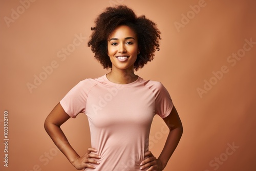 Portrait of a smiling afro-american woman in her 20s wearing a moisture-wicking running shirt isolated in soft brown background