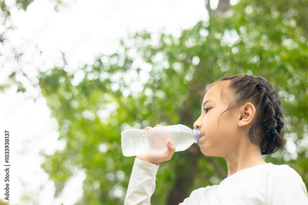 Asian child drinks water outdoors, promoting hydration and wellness with greenery background. It shows the importance of a healthy lifestyle, emphasizing refreshment and well-being in natural park. Asian child drinks water outdoors, promoting hydration and wellness with greenery background. It shows the importance of a healthy lifestyle, emphasizing refreshment and well-being in natural park.