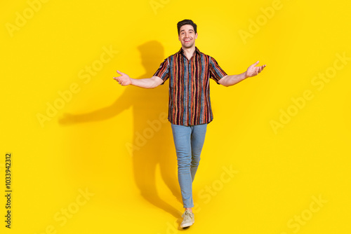 Full length portrait of nice young man walk arms welcome you wear shirt isolated on yellow color background