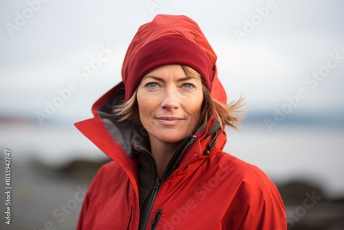 Portrait of a content woman in her 40s wearing a windproof softshell over serene seaside background photo