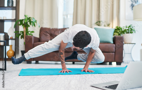 Fitness, crow pose and man with yoga in home for flexibility, mindfulness and wellness exercise. Challenge, balance and male person with kakasana position for pilates workout in living room at house. photo