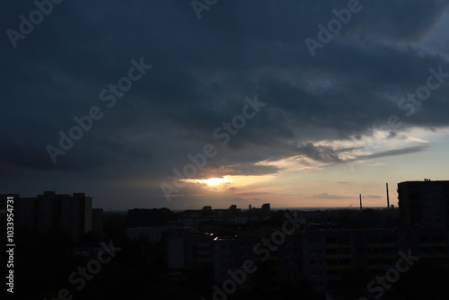 The dark sky covers the big city. The sun comes out from behind the clouds. Romantic atmosphere overlooking the evening city.