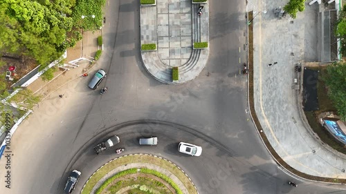 Vehicles move through a bustling roundabout Universitas Gadjah Mada surrounded by greenery and urban infrastructure photo