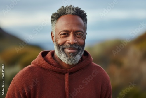 Portrait of a satisfied afro-american man in his 50s wearing a cozy sweater on serene dune landscape background