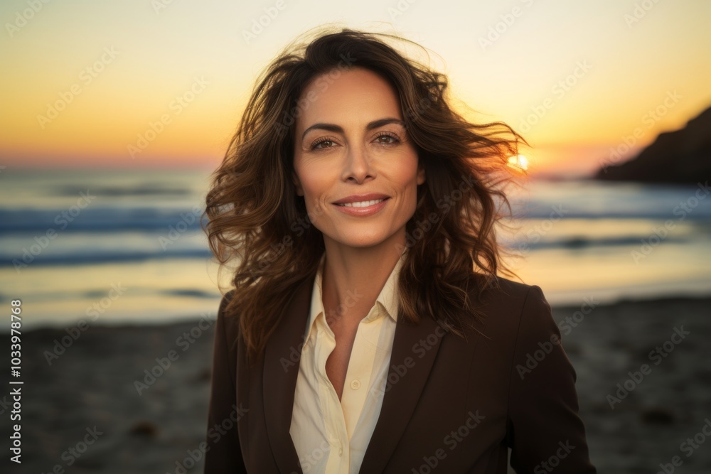 Portrait of a joyful woman in her 40s dressed in a stylish blazer isolated on vibrant beach sunset background Portrait of a joyful woman in her 40s dressed in a stylish blazer isolated on vibrant beach sunset background