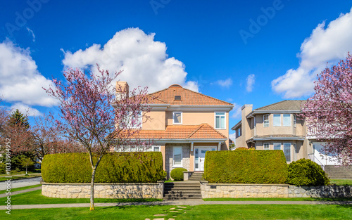 Two story stucco luxury house with nice spring blossom landscape in Vancouver, Canada