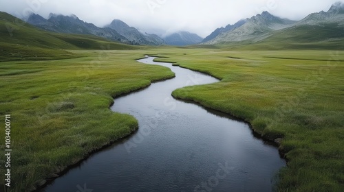 A meandering river flows gracefully through misty fields of green, framed by majestic mountain ranges, under a softly clouded sky, offering a serene retreat.