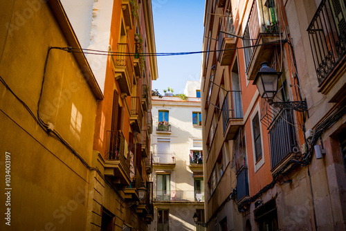 Streets of Barcelona Raval neighborhood seen on a sunny summer day with blue sky. shops, apartments balconies in the city center