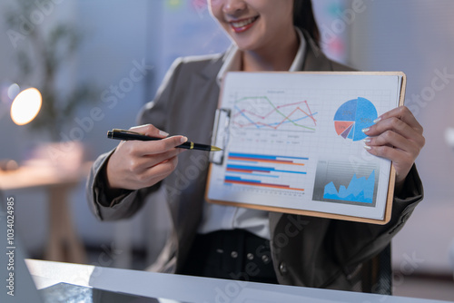 Bilde på lerret Businesswoman is pointing at charts on a clipboard with a pen while smiling