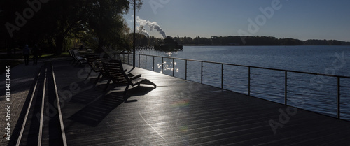 LANDSCAPE BY LAKE - Morning sun over recreational chairs on the viewing platform of city park photo