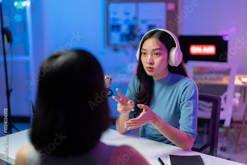 Two content creators in a studio recording a podcast with a professional microphone and headphones, fully immersed in technology