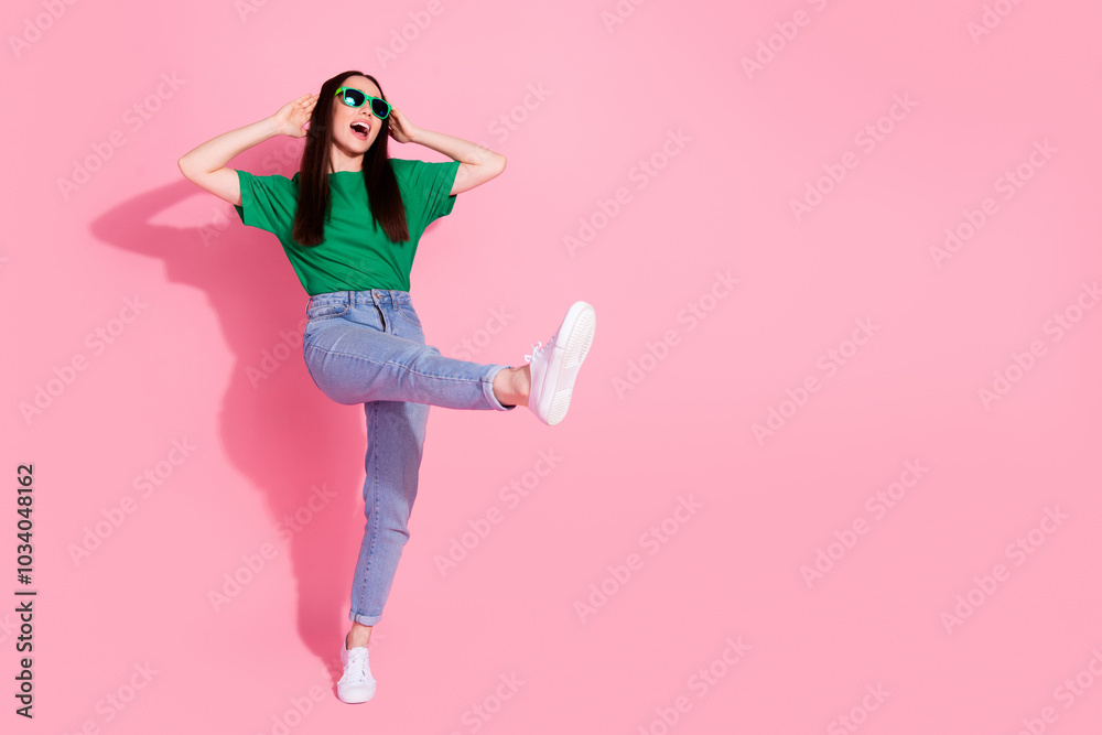 Full length photo of charming positive woman wear green t-shirt dark glasses walking empty space isolated pink color background Full length photo of charming positive woman wear green t-shirt dark glasses walking empty space isolated pink color background