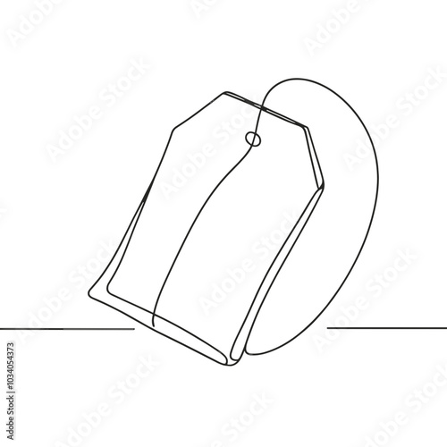 A tag is hanging from a tea bag. The tag is white and has a black border. The tea bag is sitting on a table