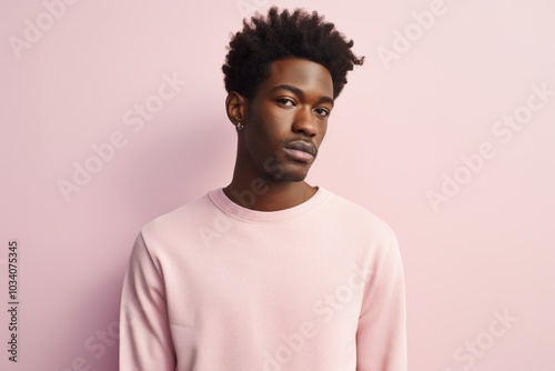 Portrait of a tender afro-american man in his 20s showing off a thermal merino wool top in front of pastel or soft colors background