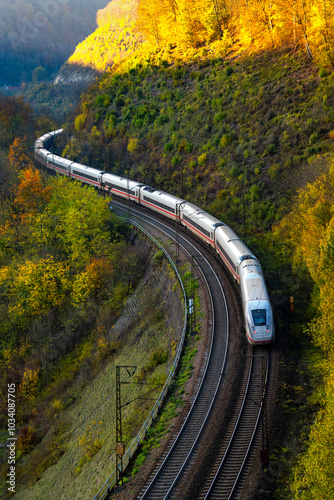 Fast train from Ulm to Stuttgart on the famous Geislinger Steige railway slope with many curves. Modern train meandring down the slope on a sunny autumn evening with colorful foliage in Germany.